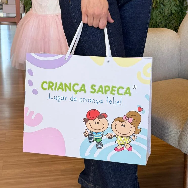 Cliente saindo de uma loja infantil carregando a sacola de papel personalizada da Criança Sapeca